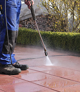 A worker performs power washing services.